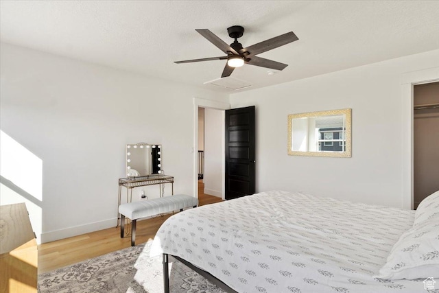 bedroom featuring a ceiling fan, wood finished floors, baseboards, attic access, and a textured ceiling