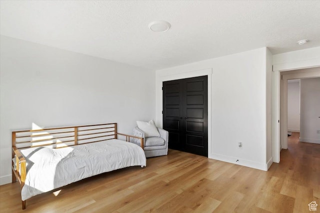 bedroom featuring wood finished floors, baseboards, and a textured ceiling