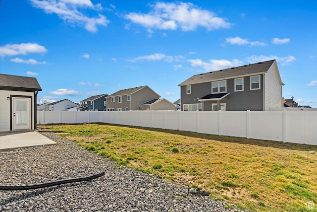 view of yard with a patio, a fenced backyard, and a residential view