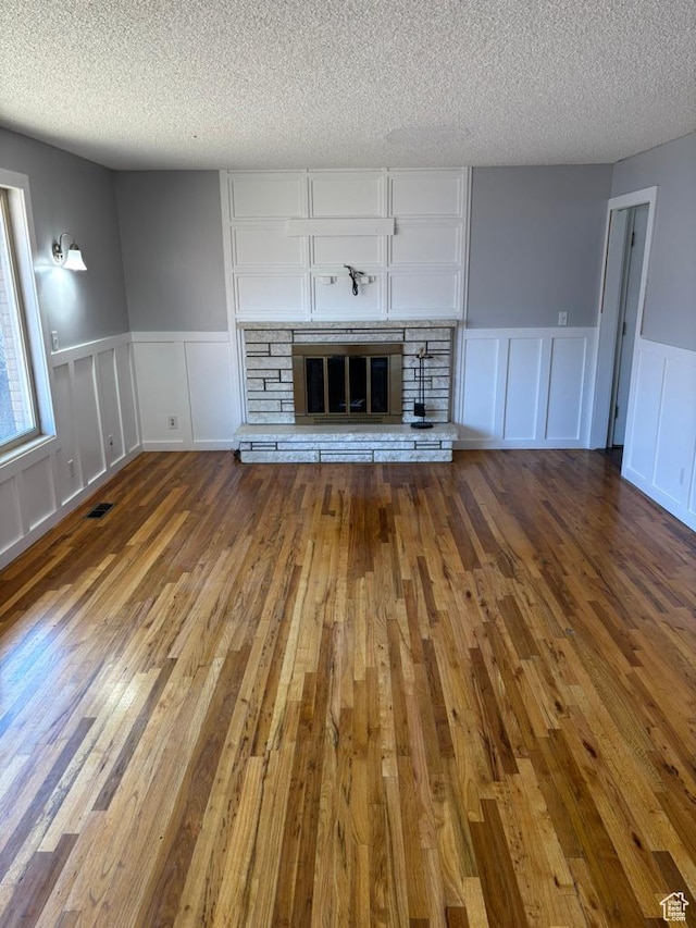 unfurnished living room featuring visible vents, a fireplace, a textured ceiling, and hardwood / wood-style floors