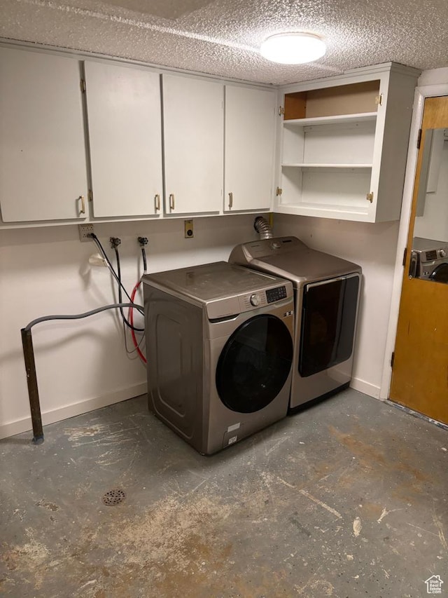 laundry room with baseboards, cabinet space, separate washer and dryer, and a textured ceiling
