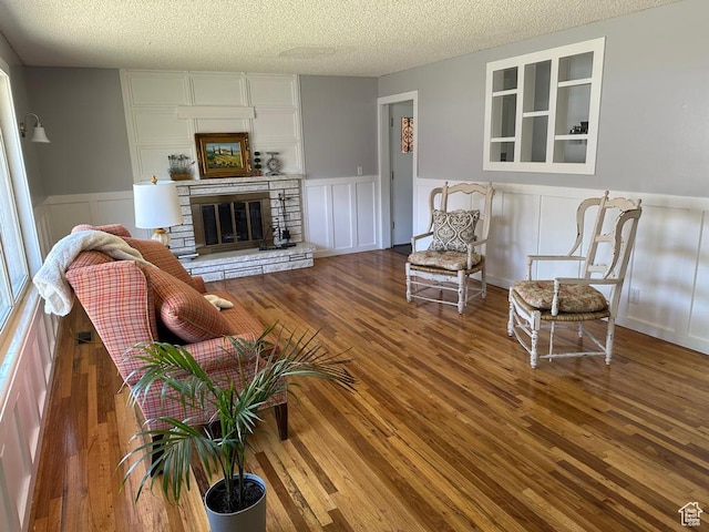 1653 S 500 E, Bountiful, UT 84010 - living room featuring a textured ceiling, wood finished floors, a wainscoted wall, a stone fireplace, and a decorative wall