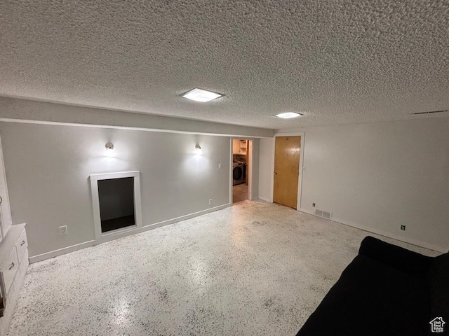 spare room with washer / clothes dryer, visible vents, speckled floor, and a textured ceiling