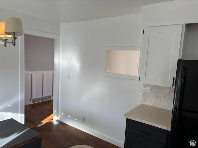 interior space featuring visible vents, dark wood finished floors, freestanding refrigerator, light countertops, and tasteful backsplash