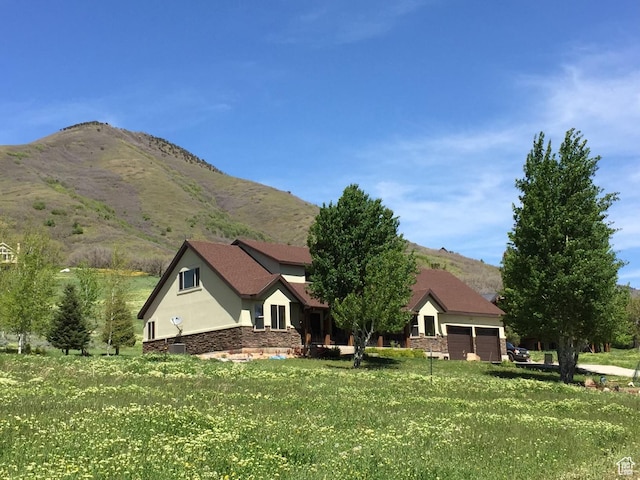 1762 S Hobblecreek Haven Rd, Springville, UT 84663 - view of front of property featuring stucco siding, a mountain view, an attached garage, stone siding, and a front lawn