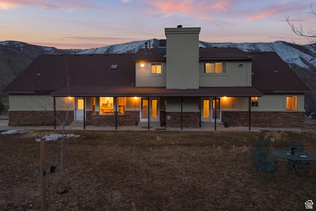 1762 S Hobblecreek Haven Rd, Springville, UT 84663 - back of property at dusk with a mountain view, stone siding, a chimney, and roof with shingles