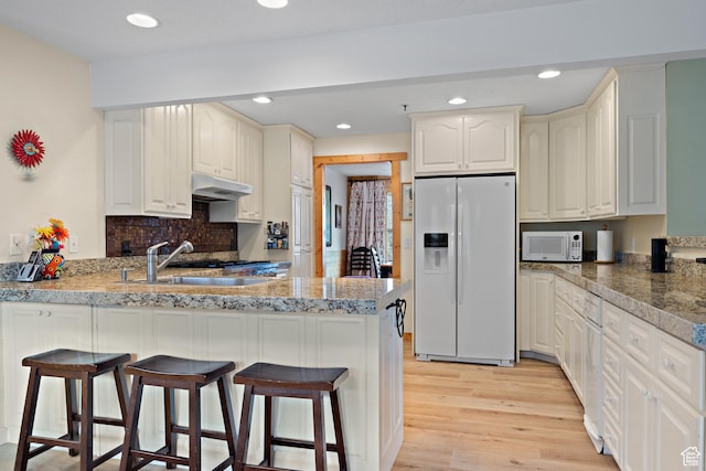 1762 S Hobblecreek Haven Rd, Springville, UT 84663 - kitchen featuring white appliances, a peninsula, light wood-type flooring, a kitchen bar, and recessed lighting