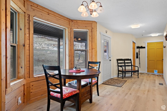 1762 S Hobblecreek Haven Rd, Springville, UT 84663 - dining area with a chandelier, light wood-type flooring, wooden walls, and a textured ceiling