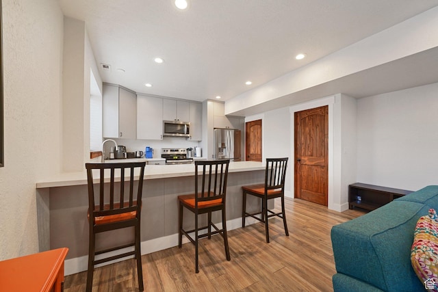 13862 S 7300 W, Herriman, UT 84096 - kitchen featuring appliances with stainless steel finishes, a peninsula, light countertops, light wood-style floors, and recessed lighting