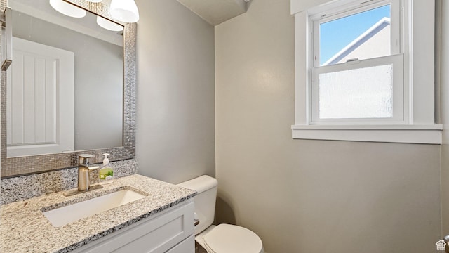 bathroom featuring toilet, vanity, and decorative backsplash