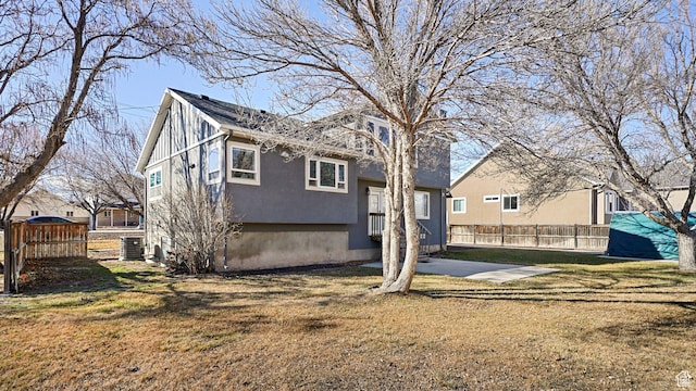 back of property featuring a lawn and fence