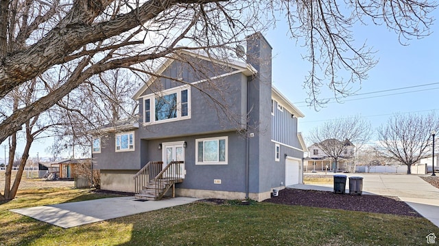 view of front of home with a chimney, a garage, stucco siding, a front lawn, and driveway