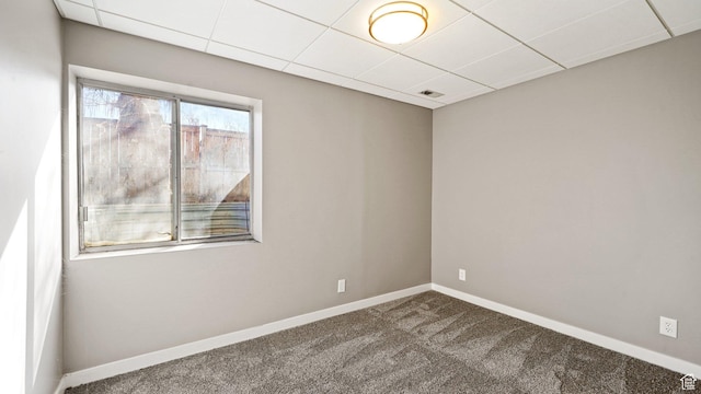 empty room featuring a drop ceiling, carpet floors, baseboards, and visible vents