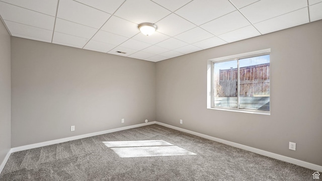 carpeted spare room featuring a drop ceiling, baseboards, and visible vents