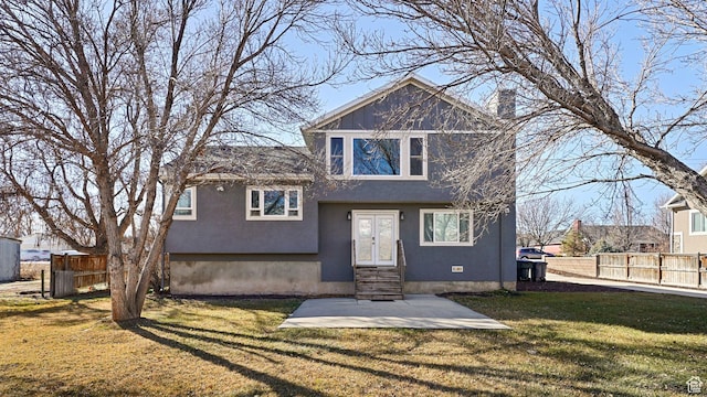 view of front of property with entry steps, stucco siding, fence, and a front lawn