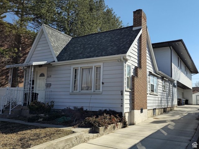 view of front of home featuring a chimney and a shingled roof