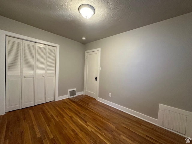 unfurnished bedroom with visible vents, baseboards, a closet, and wood finished floors