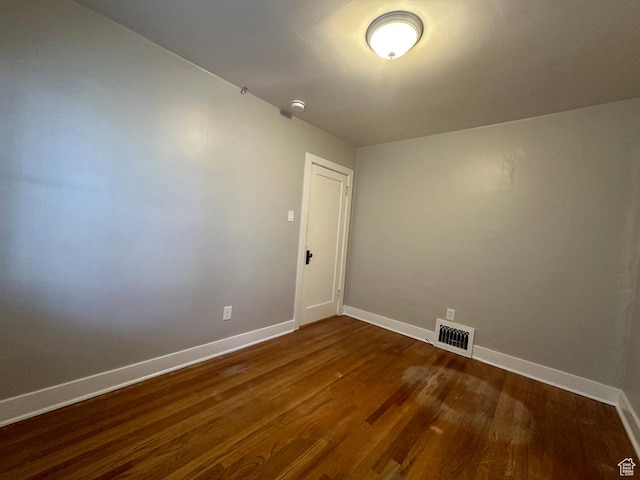spare room with visible vents, baseboards, and dark wood-style floors