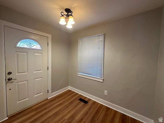 foyer with visible vents, an inviting chandelier, dark wood-type flooring, and baseboards