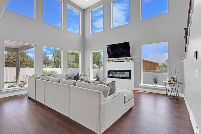 living area with dark wood finished floors, a glass covered fireplace, and baseboards