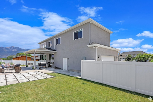 rear view of property with a patio, a yard, a fenced backyard, stucco siding, and a mountain view