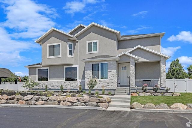 view of front of house with a gate, fence, stone siding, and stucco siding