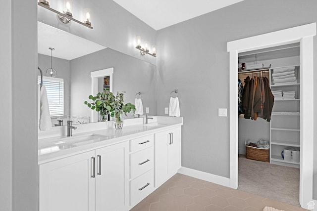 full bathroom featuring a sink, a walk in closet, baseboards, and double vanity