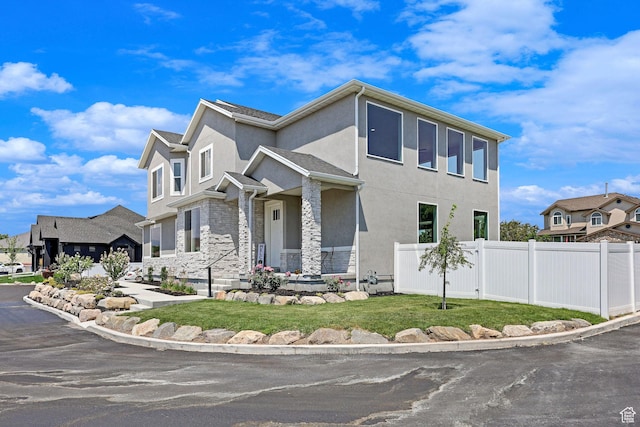 view of front facade featuring fence, stone siding, and stucco siding