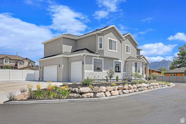view of front facade featuring stucco siding, stone siding, driveway, and fence