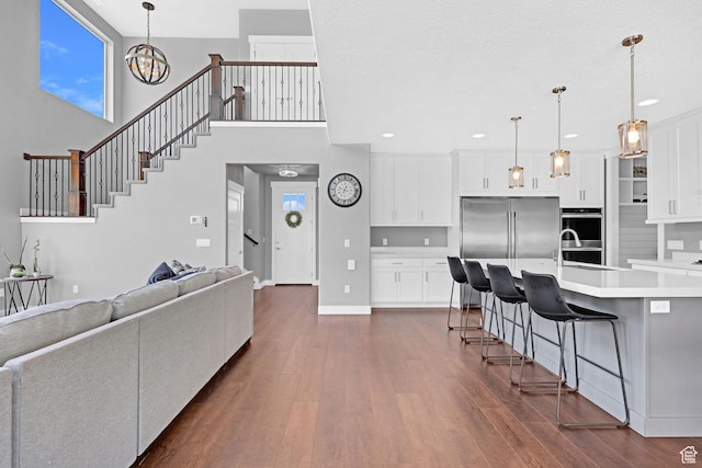 living room with baseboards, a high ceiling, recessed lighting, dark wood-style flooring, and stairs