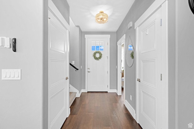 entrance foyer featuring stairway, dark wood-type flooring, and baseboards