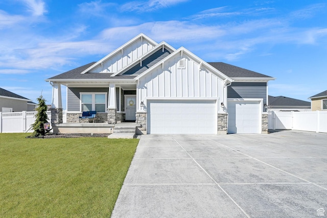 view of front of house with a front yard, fence, an attached garage, concrete driveway, and board and batten siding