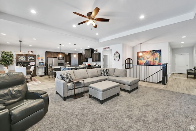 living area featuring recessed lighting, a tray ceiling, a ceiling fan, and light wood finished floors