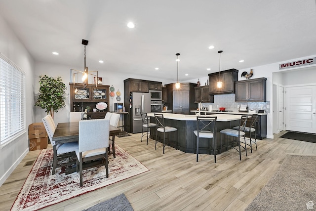 kitchen featuring visible vents, stainless steel appliances, light countertops, decorative backsplash, and dark brown cabinets