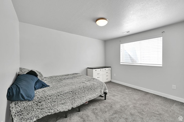 bedroom featuring visible vents, a textured ceiling, baseboards, and carpet floors