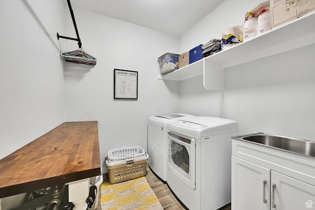 washroom featuring light wood-type flooring, cabinet space, and independent washer and dryer