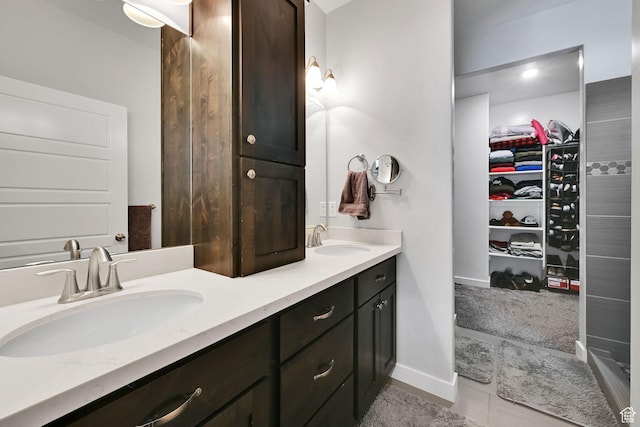 bathroom featuring double vanity, a spacious closet, baseboards, and a sink
