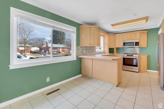 kitchen featuring a peninsula, appliances with stainless steel finishes, ornamental molding, and light brown cabinets