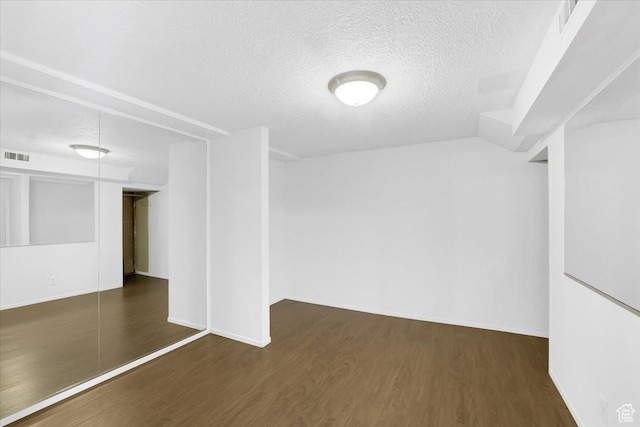 spare room with baseboards, wood finished floors, visible vents, and a textured ceiling