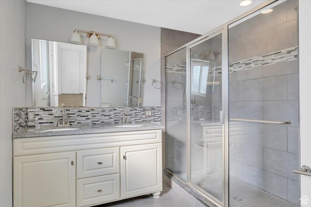 bathroom with double vanity, a stall shower, and a sink