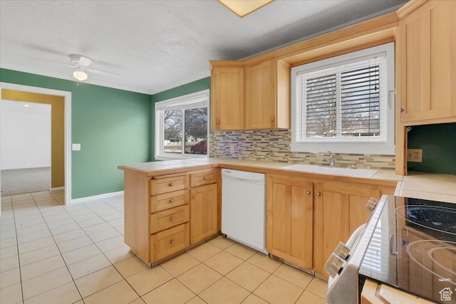kitchen with light tile patterned floors, a peninsula, white dishwasher, a sink, and tile counters