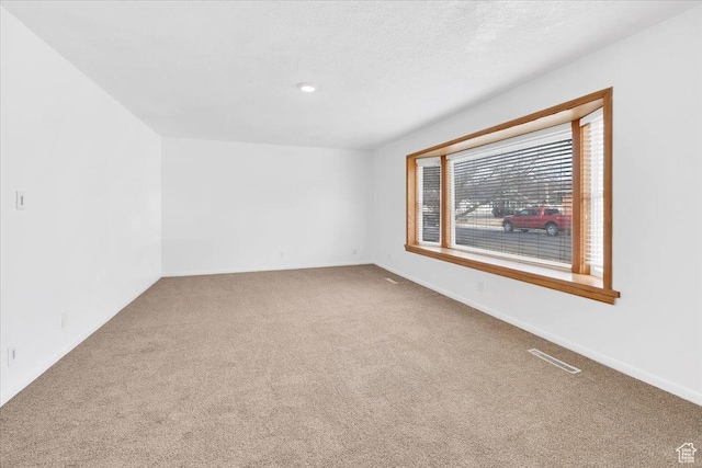 empty room with baseboards, carpet, visible vents, and a textured ceiling