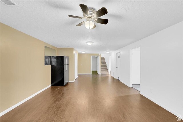 unfurnished living room featuring baseboards, dark wood-style flooring, ceiling fan, stairs, and a textured ceiling