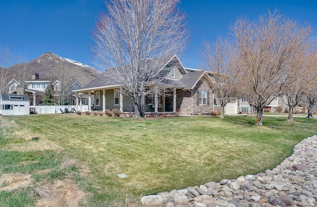 exterior space featuring a front yard, a mountain view, fence, and covered porch