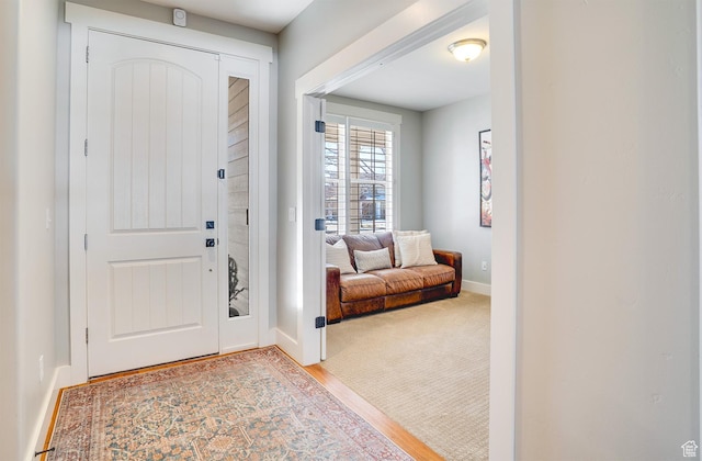foyer entrance featuring carpet flooring and baseboards