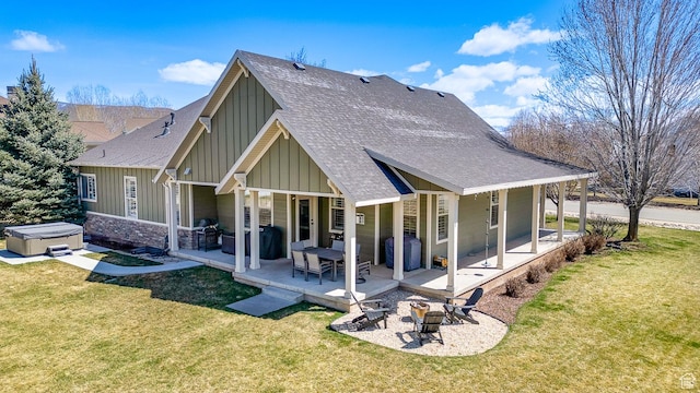 back of property featuring a shingled roof, a hot tub, an outdoor fire pit, board and batten siding, and a patio