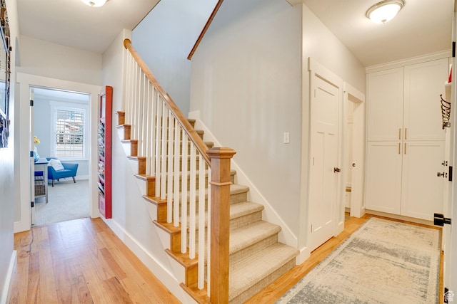 entrance foyer featuring stairs, light wood-type flooring, and baseboards