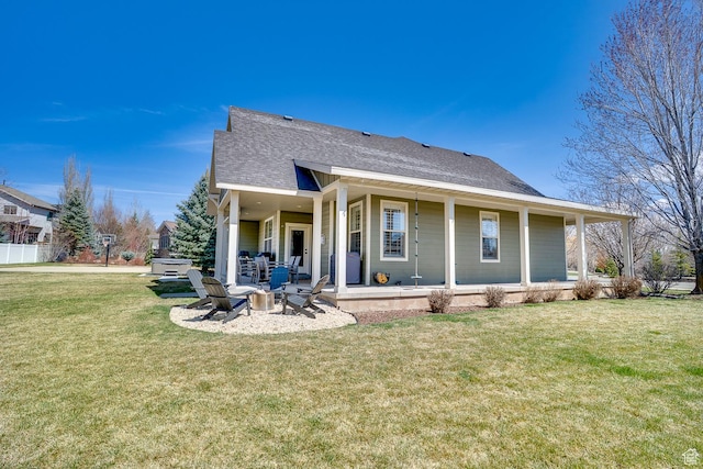 rear view of house featuring an outdoor fire pit, a shingled roof, a patio area, and a lawn