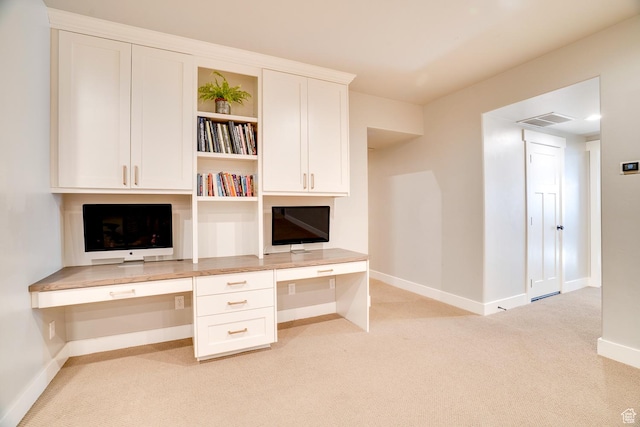unfurnished office featuring baseboards, light colored carpet, built in study area, and visible vents