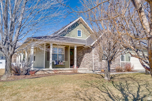 view of front of home with roof with shingles, a porch, stone siding, and a front lawn